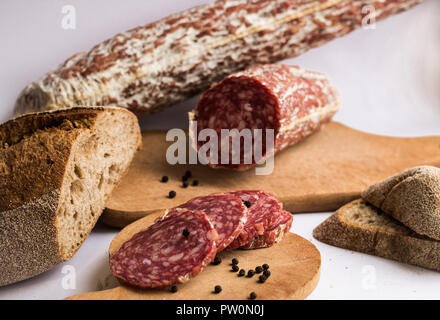 Wurst mit Pfeffer und Brot auf weißem Hintergrund Stockfoto