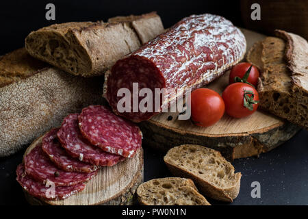 Wurst mit Stücken, Brot und Kartoffeln isoliert auf Schwarz Stockfoto