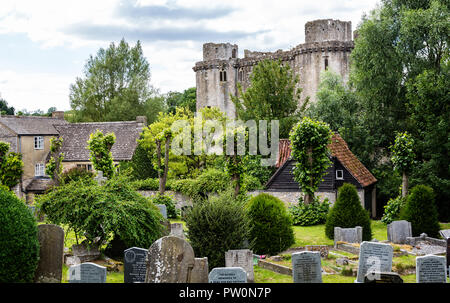 Nunney Schloss mit Kirche grave Yards im Vordergrund im Nunney, Somerset, Großbritannien am 13. Juli 2014 Stockfoto