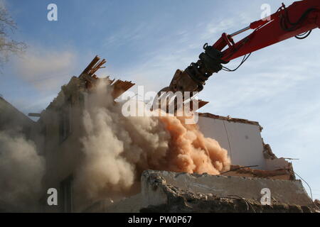 Reißen Sie ein altes Gebäude mit einem Bagger Stockfoto