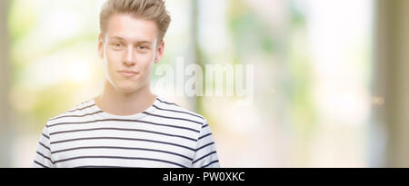 Jungen gutaussehenden blonden Mann Streifen tragen SAILOR T-Shirt mit einem selbstbewussten Ausdruck auf Smart Face denken Ernst Stockfoto