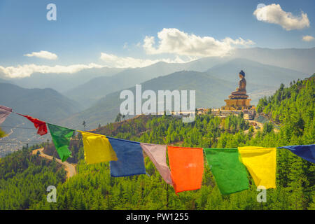 Paro Buddha mit Gebetsfahnen im Vordergrund und das Tal im Hintergrund Stockfoto