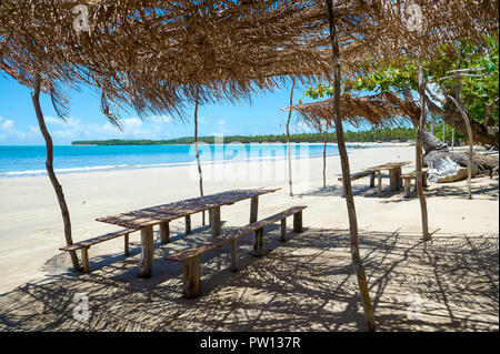 Helle malerischen Blick auf Holz- Picknick Tischen unter rustikale Brasilianischen Palapas auf einer einsamen Strand in Bahia, Brasilien Stockfoto