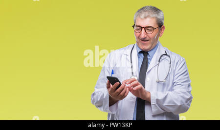 Stattliche leitender Arzt Mann sms senden Nachricht mit Smartphone über isolierte Hintergrund mit einem glücklichen Gesicht stehen und lächelnd mit einem selbstbewussten Stockfoto