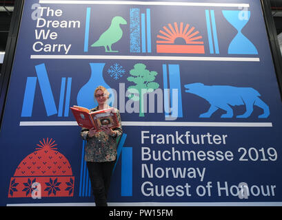 Frankfurt am Main, Deutschland. 11 Oktober 2018, Hessen, Frankfurt Main: Auf der Frankfurter Buchmesse, wird eine Frau blättert in einem Buch vor einem großen Plakat an der gemeinsamen Norwegen stehen. Norwegen ist der Ehrengast der Buchmesse 2019. Größte Buch der Welt zeigen wird, bis 14. Oktober statt. Foto: Arne Dedert/dpa Stockfoto