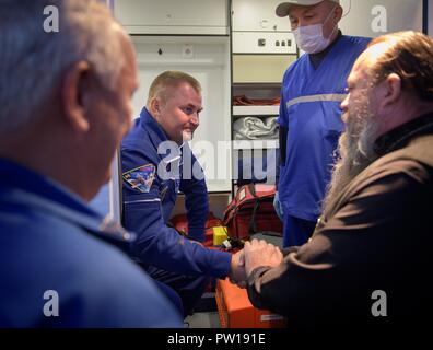 Internationale Raumstation ISS Expedition 57 Alexey Ovchinin von Roskosmos, Mitte, wird von Russischen orthodoxen Priester Vater Sergej nach der Landung am Flughafen Krayniy nach einem Abbruch während liftoff in der russischen Sojus-Rakete Oktober 11, 2018 in Baikonur, Kasachstan, begrüßt. Kurz nach dem Abheben der Rakete versagt auf dem Weg zur Internationalen Raumstation und Abgebrochen zwingt eine Notlandung in Kasachstan. Stockfoto