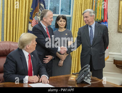 Washington, District of Columbia, USA. 11 Okt, 2018. United States Senator Dan Sullivan (Republikaner von Alaska), Mitte links, schüttelt Hände mit US-Senator Sheldon Whitehouse (Demokrat von Rhode Island), rechts, als US-Präsident Donald J. Trumpf, Links, und Julie Schicksal, Ehefrau von Senator Sullivan, Mitte rechts, sehen Sie auf wie der Präsident Bemerkungen macht vor S.3508, der 'Save Unsere Meere Act von 2018'' Unterzeichnung im Oval Office des Weißen Hauses in Washington, DC am Donnerstag, 11. Oktober 2018. Credit: Ron Sachs/CNP Stockfoto