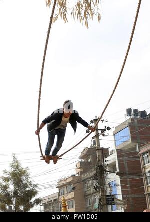 Kathmandu, Nepal. 12 Okt, 2018. Ein Jugendlicher spielt auf einer traditionellen Swing in der Feier der Dashain Festival in Kathmandu, Nepal, Okt. 12, 2018. Credit: Sunil Sharma/Xinhua/Alamy leben Nachrichten Stockfoto