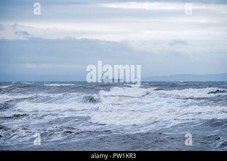 Stürmisches Wetter über Saltcoats Bay in Schottland, wie die Wellen höher und ein Unbekannter Frachter, die in den Fluss Clyde aus Saltcoats erhalten. Stockfoto