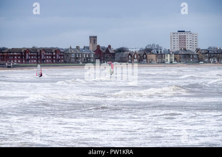 Stürmisches Wetter über Saltcoats Bay in Schottland, wie die Wellen pound den Hafen und zwei Wind surfer Nutzen einen Sturm in Saltcoats Bay Scotlan Stockfoto