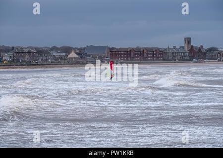 Stürmisches Wetter über Saltcoats Bay in Schottland, wie die Wellen pound den Hafen einer einzigen Windsurfer nutzt die dunstige Sturm Stockfoto