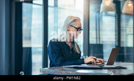Reife Geschäftsfrau Arbeiten am Laptop Computer an Ihrem Arbeitsplatz. Ältere Frau mit Laptop im Büro. Stockfoto