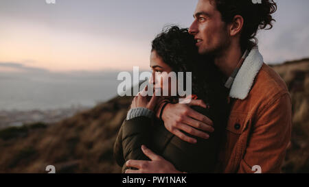 Seitenansicht des zärtlich Paar umarmen und weg schauen. Mann und Frau zusammen auf den Berg auf einen Blick. Stockfoto