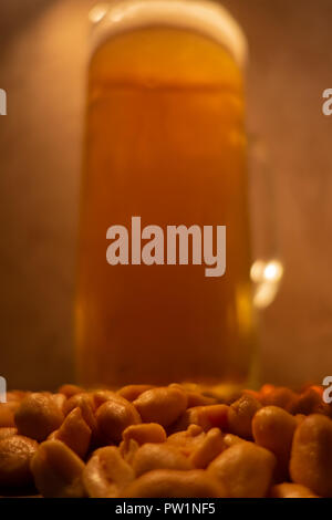 Glas Licht kalt schaumiges Bier, Muttern an einem alten Holztisch. Stockfoto