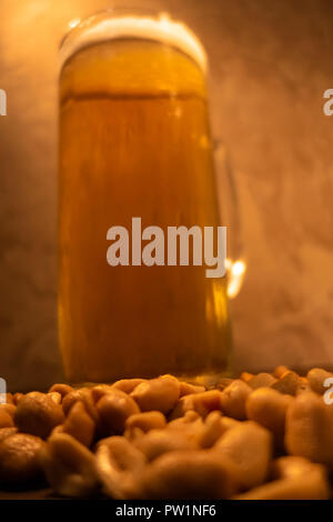 Glas Licht kalt schaumiges Bier, Muttern an einem alten Holztisch. Stockfoto