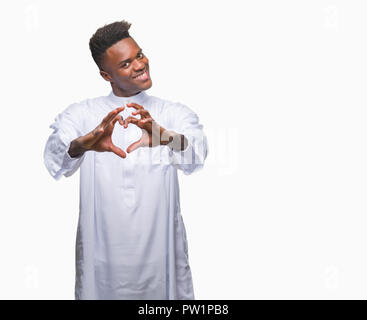 Junge arabische afrikanischen Mann mit traditionellen djellaba über isolierte Hintergrund in der Liebe mit Herz und mit Hand lächelnd. Romantische con Stockfoto