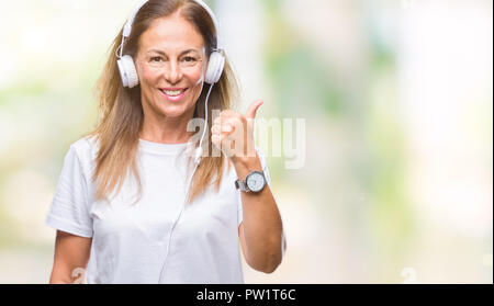 Mittleres Alter Hispanic Frau Musikhören mit Kopfhörern über isolierte Hintergrund tun glücklich Daumen nach oben Geste mit der Hand. Die Genehmigung der Ausdruck Stockfoto