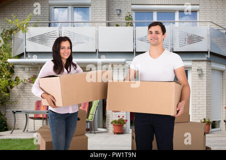 Porträt eines glückliches junges Paar hält Karton Vor Ihrem Haus Stockfoto