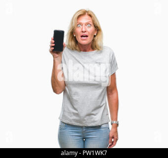 Blonde Frau mittleren Alters mit leerer Bildschirm des Smartphones über isolierte Hintergrund im Schlag mit einer Überraschung konfrontiert, ängstlich und aufgeregt mit Angst Angst Stockfoto