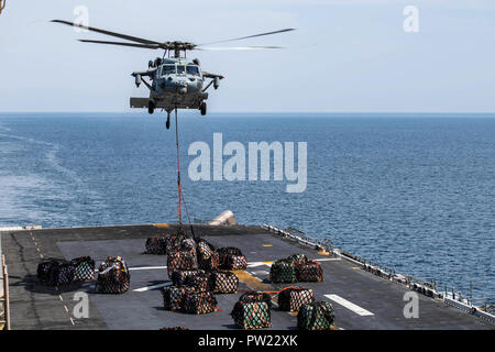 181008-N-NI 420-1039 Arabische Meer (Okt. 2010) 8, 2018) - einem MH-60S Sea Hawk Hubschrauber, zugeordnet zu den "Blackjacks" der Hubschrauber Meer Combat Squadron (HSC) 21, liefert sie die Ladung der Flight Deck von Wasp-Class amphibisches Schiff USS Essex (LL 2), während in einer vertikalen Auffüllung teilnehmenden während einer planmäßigen Einsatz von Essex Amphibious Ready Group (ARG) und 13th Marine Expeditionary Unit (MEU). Der Essex ist eine tödliche, flexibel, und anhaltende Navy-Marine Corps Team in die USA 5 Flotte Bereich der Maßnahme zur Unterstützung der Marineoperationen bereitgestellt maritime Stabilität und Secur zu gewährleisten Stockfoto
