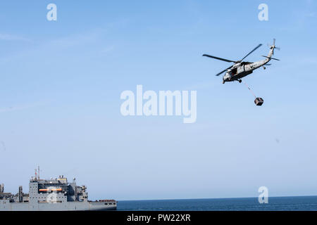 181008-N-NI 420-1281 Arabische Meer (Okt. 2010) 8, 2018) - einem MH-60S Sea Hawk Hubschrauber, der "Blackjacks" der Hubschrauber Meer Combat Squadron (HSC) 21, Transporte Fracht zugewiesen während einer vertikalen Nachschub zwischen Dry Cargo und Munition ship USNS Alan Shepard (T-AKE 3), links, und Wasp-Class amphibisches Schiff USS Essex (LHD2) und während einer planmäßigen Einsatz von Essex Amphibious Ready Group (ARG) und 13th Marine Expeditionary Unit (MEU). Der Essex ist eine tödliche, flexibel, und anhaltende Navy-Marine Corps Team in die USA 5 Flotte Bereich der Maßnahme zur Unterstützung der Naval Oper bereitgestellt Stockfoto