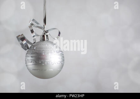 Silber Weihnachten Silvester Ball mit Curly streamer Schleife über glitzernde bokeh Lichter Hintergrund mit Platz für Text kopieren Stockfoto