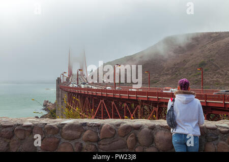 Frau steht im VIsta Point an der Golden Gate Bridge auf der Suche an einem nebligen Morgen, San Francisco, Kalifornien, USA. Stockfoto