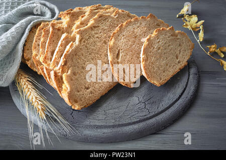 Slliced weiße runde Brot mit Weizen Ohren auf Grau rustikalen Holztisch Stockfoto