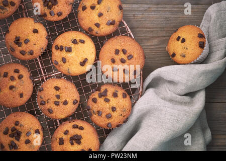 Zwölf frisch gebackene choco Chip muffins Abkühlen auf Drahtgeflecht auf Holz mit Bettwäsche Handtuch, Flachbild Layout Stockfoto