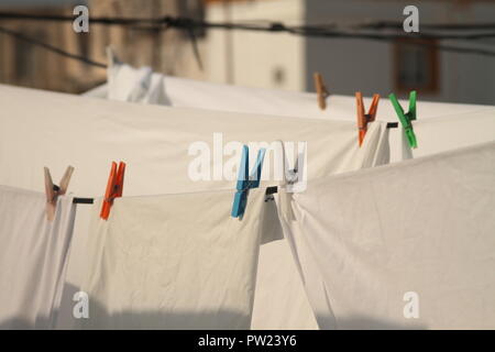 Weiße Bettwäsche und Kleidung von der Trocknung Leitungen geklemmt hängend, in einer kleinen Stadt am Mittelmeer auf dem Dach. Stockfoto