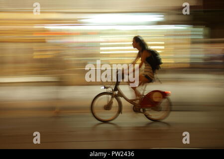 Motion Blur: eine Frau reitet ein Gemeinschafts-Fahrrad in einer animierten Urban Street in Sevilla, Spanien. Stockfoto