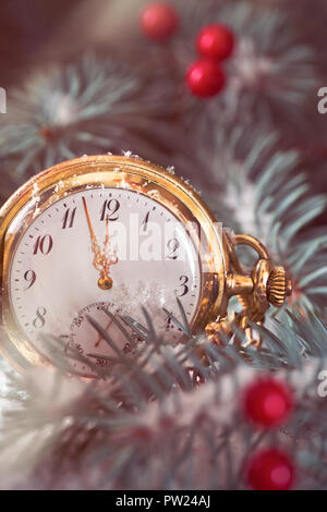 Close-up auf antike Taschenuhr zeigt fünf bis zwölf Unter den Tannen Zweigen, roten Beeren und Schnee Stockfoto