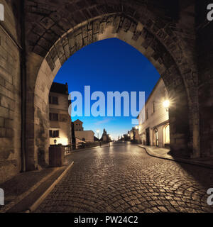 Prag in der Morgendämmerung, Eingang zur Karlsbrücke durch die beleuchteten Bogen von Lesser Town Bridge Tower in den frühen Morgenstunden. Panoramic Image, sq Stockfoto