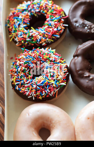 Bunte Streusel über Schokoladen Donuts aus Krispy Kreme Stockfoto
