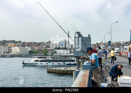 Eine Gruppe von Fischer auf der Galata Brücke mit ihren Angelruten über der Seite als Fähre, Istanbul, Türkei Pässe Stockfoto
