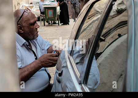 Jerusalem, Israel. 11. Oktober, 2018. Eine ältere muslimisch-arabischen Mann leuchtet eine Zigarette in der Nähe der Chain Tor Jerusalems Tempelberg. Stockfoto