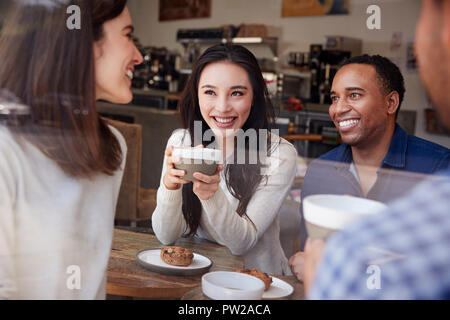 Vier lächelnden Freunde Kaffee im Coffeeshop, in der Nähe Stockfoto