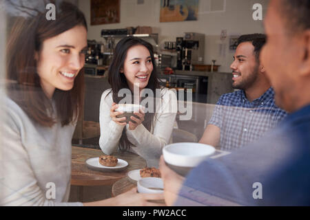 Vier lächelnd nach Freunde sitzen in Kaffee bei Coffee Shop Stockfoto