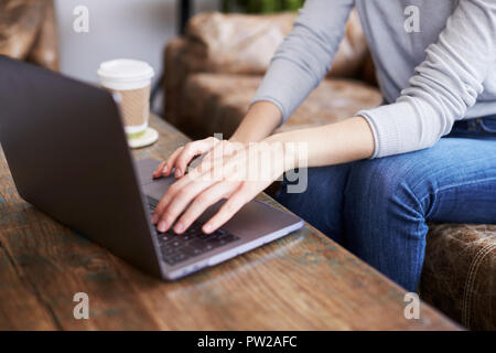 Junge Frau mit Laptop in einem Coffee Shop, mittlere Partie Stockfoto