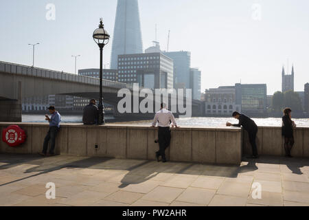 Londoner Arbeiter und Angestellten in der Londoner City - der Capital District - genießen Sie den Spätsommer Temperaturen auf der Fischhändler Halle Wharf mit Blick auf die Wolkenkratzer Shard, London Bridge und der Themse, am 10. Oktober 2018, in London, England. Stockfoto