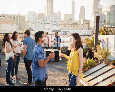 Freunde versammelt Auf der Dachterrasse für Party mit Sicht auf die City Skyline im Hintergrund Stockfoto