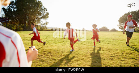 Schüler spielen Fußball mit Ihrem Trainer Stockfoto