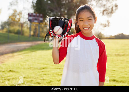 Junge Chinesin holding Baseball in mitt blickt in die Kamera Stockfoto