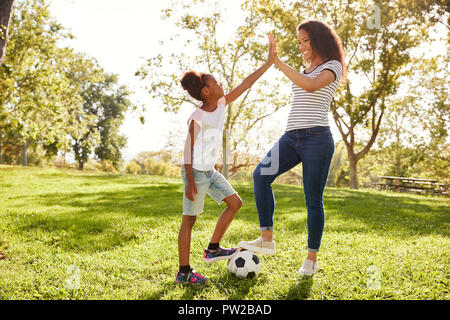 Mutter und Tochter Fußball spielen im Park zusammen Stockfoto