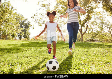 Mutter und Tochter Fußball spielen im Park zusammen Stockfoto