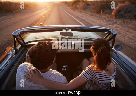 Ansicht der Rückseite des Paar auf Autofahrt Classic Cabrio Auto Richtung Sonnenuntergang Stockfoto