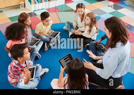 Lehrer und Kinder in einer Grundschule Lektion mit Tabletten Stockfoto
