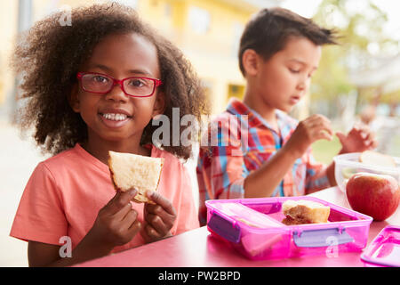 Junge Mädchen und Jungen mit lunchpakete Blick zur Kamera Stockfoto