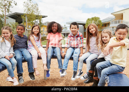 Grundschule Kinder sitzen auf Karussell auf dem Schulhof Stockfoto