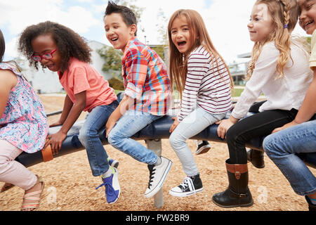 Kinder spielen auf ein sich drehendes Karussell in ihren Schulhof Stockfoto